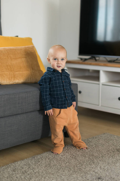 Caucasian baby newborn infant making first steps. Cute toddler kid child son boy learning walking creeping on living room. Childcare and childhood - Fotoğraf, Görsel