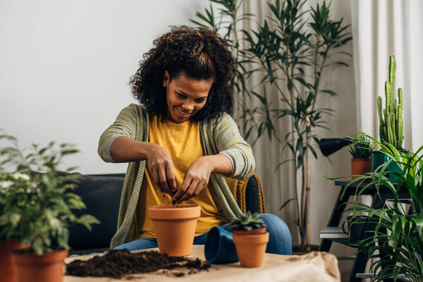 Happy woman fills the flower pot with soil - Фото, изображение