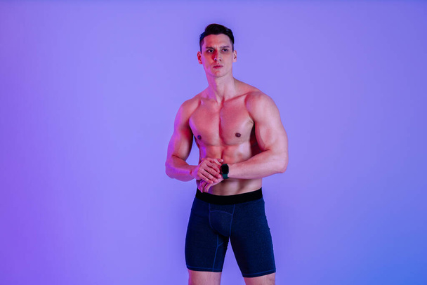 Athletic man with fit muscular body training in studio - Active man doing a workout, colorful lighting and background, concepts about fitness, sport and health lifestyle - Foto, Bild