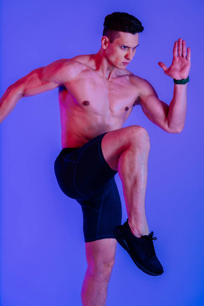 Athletic man with fit muscular body training in studio - Active man doing a workout, colorful lighting and background, concepts about fitness, sport and health lifestyle - 写真・画像
