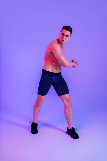 Athletic man with fit muscular body training in studio - Active man doing a workout, colorful lighting and background, concepts about fitness, sport and health lifestyle - Fotografie, Obrázek