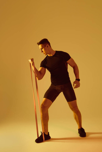 Athletic man with fit muscular body training in studio - Active man doing a workout, colorful lighting and background, concepts about fitness, sport and health lifestyle - Photo, image