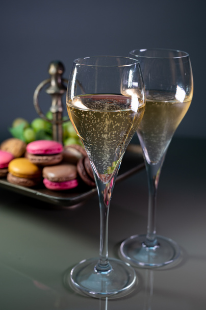 Glasses of sparkling white wine champagne brut or cava with bubbles and sweet dessert colorful macarons biscuits on background - Foto, Imagem