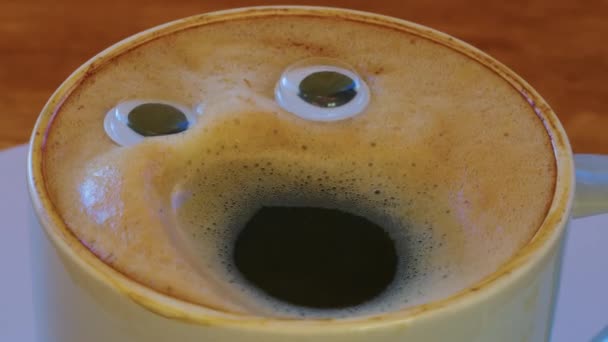 Close-up coffee cup with eyes and mouth screaming very loudly. Emoji coffee. Cheerful mood of the barista who made coffee with a human face. High quality 4k footage - Imágenes, Vídeo