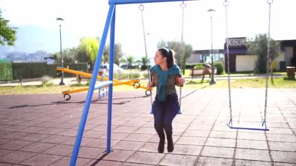 Giovane donna che oscilla su un'altalena al parco giochi. Filmati 4k di alta qualità - Filmati, video