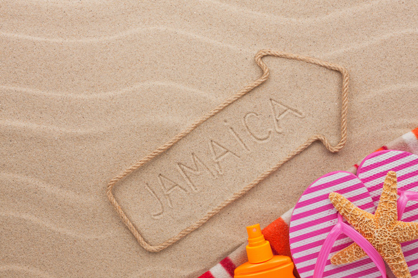 Jamaica  pointer and beach accessories lying on the sand - Φωτογραφία, εικόνα