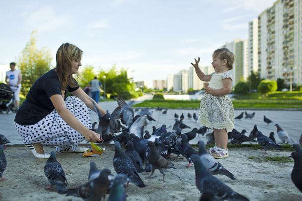 Little girl and mother feeding pigeons urban blue-gray - Foto, Imagem