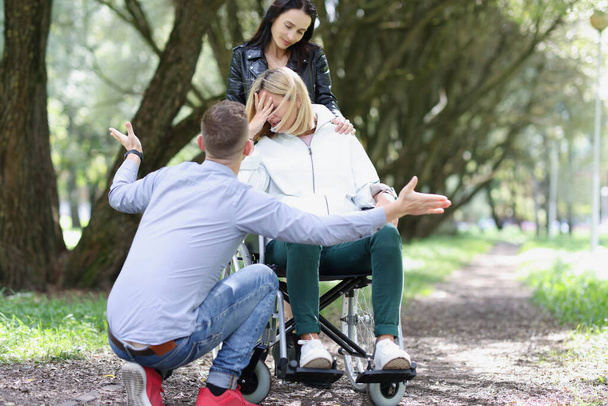 Portrait of disabled unhappy woman in wheelchair with friend. Support and friendship concept - 写真・画像