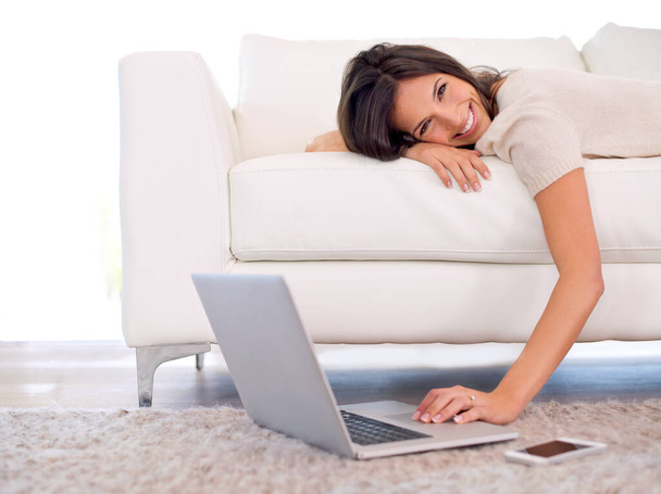 Vágott felvétel egy gyönyörű fiatal nőről, aki a kanapén fekszik egy laptoppal.. - Fotó, kép