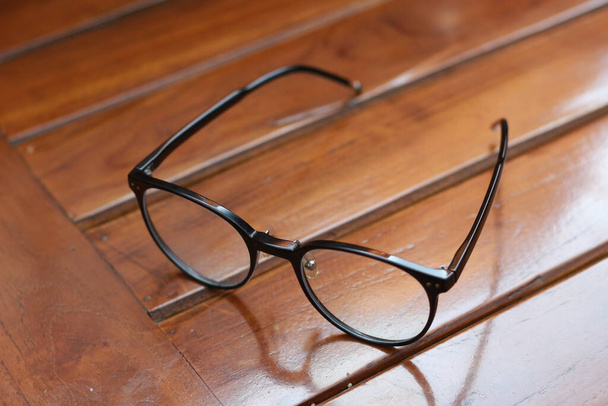 eine Nahaufnahme der Brille mit schwarzem Rahmen isoliert natürlich gemusterten Holzhintergrund. - Foto, Bild