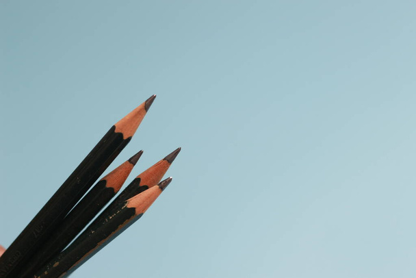 a close up of a bunch of pencils isolated on a blue background. creative photo concept. - Фото, зображення