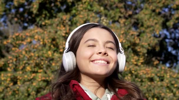 Zeitlupe fröhlicher Teenie-Mädchen, die über Kopfhörer Musik hören. Teenager-Mädchen mit Kopfhörern hören Musik. Kindheit von Teenagermädchen, die Musik über drahtlose Kopfhörer hören. Teenager-Mädchen hören Musik über Kopfhörer. - Filmmaterial, Video