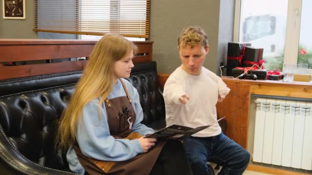 молодий чоловік з обмеженими можливостями обговорює стрижку зі своїм господарем у перукарні
 - Кадри, відео