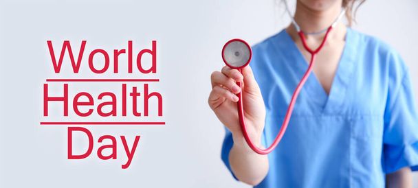 Ärztin mit Stethoskop auf hellem Hintergrund. Weltgesundheitstag - Foto, Bild