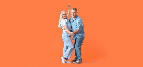 Dancing mature couple on orange background - Foto, afbeelding