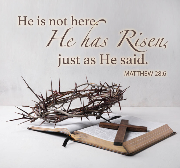 Text HE IS NOT HERE. HE IS RISEN, JUST AS HE SAID with crown of thorns, cross and Holy Bible on light background - Photo, Image