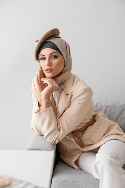 Stylish Muslim woman sitting on sofa at home - Foto, Imagen