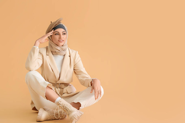 Elegante mujer musulmana sentada sobre fondo beige - Foto, imagen