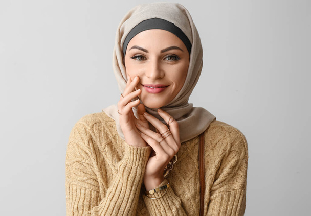Stylish Muslim woman in beige hijab on light background, closeup - Foto, imagen