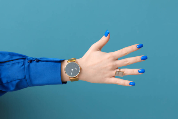 Woman with golden wristwatch on blue background - Foto, Imagem
