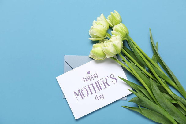 Greeting card with text HAPPY MOTHER'S DAY and beautiful tulip flowers on blue background - Valokuva, kuva