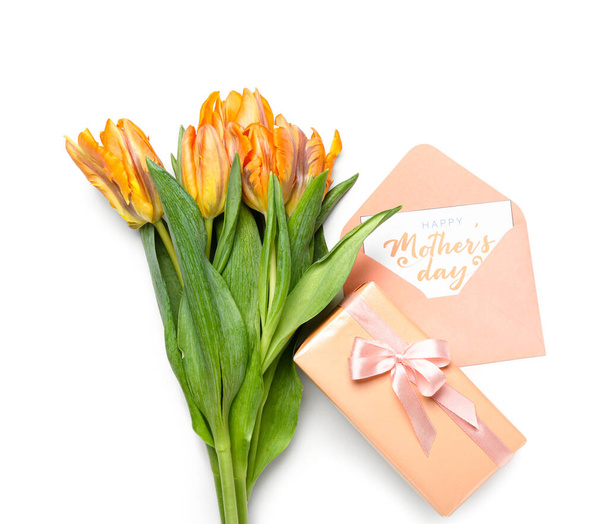 Összetétel üdvözlőkártyával, ajándékdobozzal és tulipánvirágokkal fehér alapon. Anyák napi ünneplés - Fotó, kép