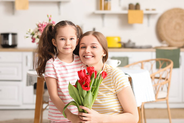 Roztomilá holčička a její matka s tulipány v kuchyni - Fotografie, Obrázek