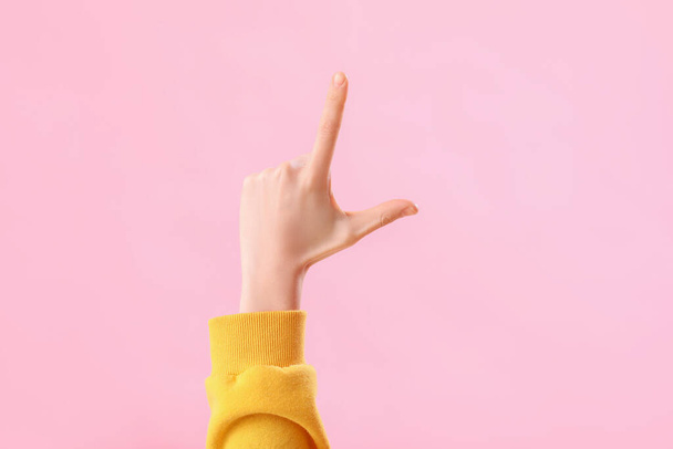 Mujer joven mostrando gesto perdedor sobre fondo rosa - Foto, imagen