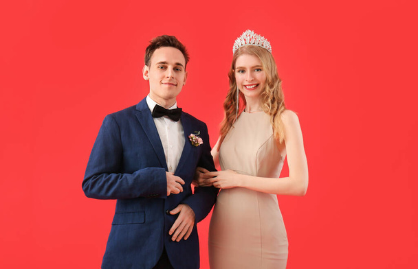 Красивая пара, одетая для выпускного бала на красном фоне - Фото, изображение