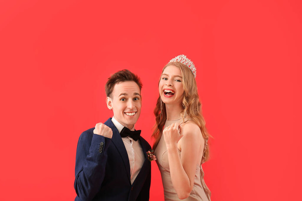 Ευτυχισμένο νεαρό ζευγάρι ντυμένο για το χορό στο κόκκινο φόντο - Φωτογραφία, εικόνα