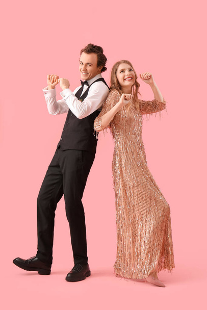 Beautiful couple dressed for prom dancing on pink background - Φωτογραφία, εικόνα