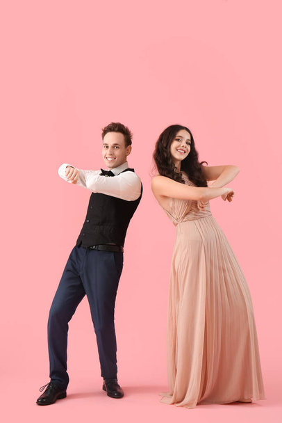 Beautiful couple dressed for prom dancing on pink background - Foto, immagini