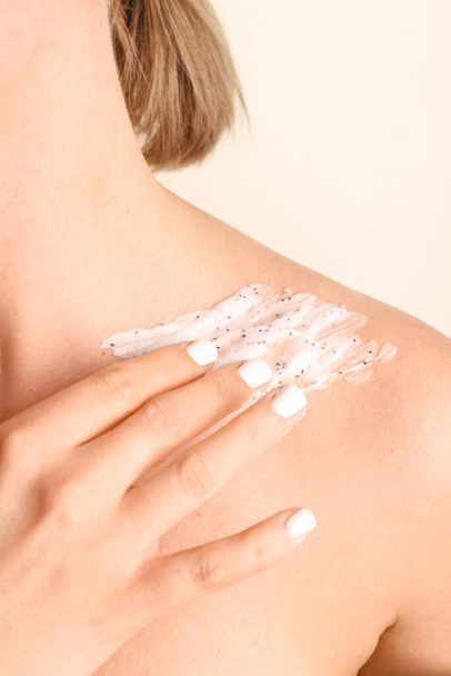 Woman applying scrub on her shoulder against color background, closeup - Photo, Image