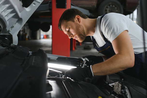Auto mechanic working on car engine in mechanics garage. Repair service - Zdjęcie, obraz