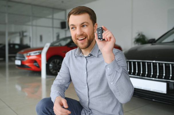 Young man is choosing a new vehicle in car dealership - Фото, зображення