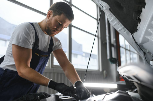 Auto mechanic working on car engine in mechanics garage. Repair service - Foto, Bild