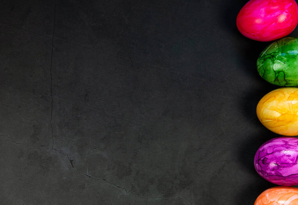 Elegante sfondo con uova di Pasqua dipinte colorate isolato su sfondo di cemento scuro per il web design. Posa piatta, vista dall'alto, mockup, spazio di copia sopraelevato Buon concetto di Pasqua Vacanze - Foto, immagini