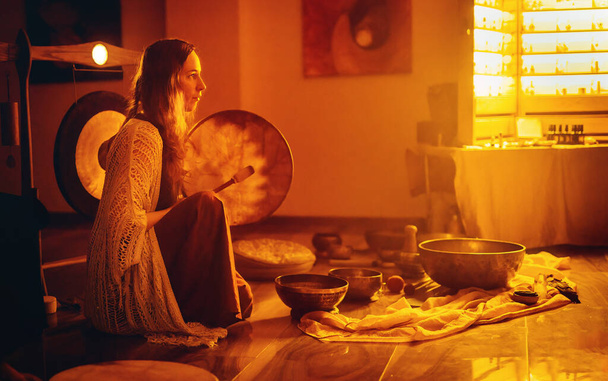 beautiful woman playng on tibetan bowl and shaman drum, ceremonial space - Foto, Imagem