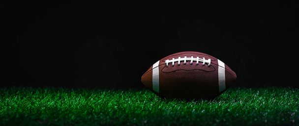 American football on green grass, on black background. Horizontal sport theme poster, greeting cards, headers, website and ap - Photo, Image