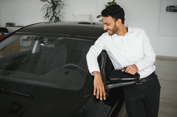 happy indian man checking car features at showroom. - Fotó, kép