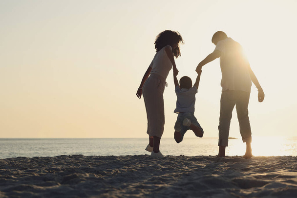 Silhouette, mock up and a family on a beach, playing while having fun together by the ocean or sea. Kids, travel or love with a mother, father and child on the sand at the coast to play while bonding. - Photo, Image