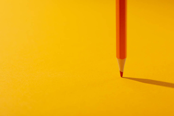 Orange pencil on yellow background, space for text - Zdjęcie, obraz