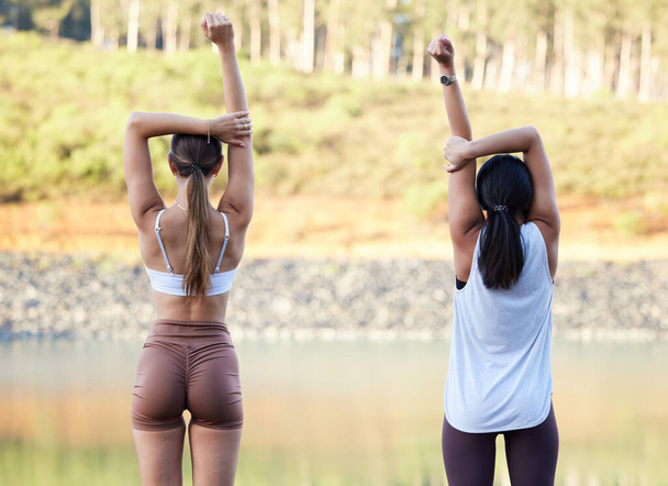 Exercise, stretching and women outdoor in nature for fitness, peace and wellness. Young friends or people warm up at forest lake for workout, training and energy for mental health, chakra and zen. - Foto, Imagem