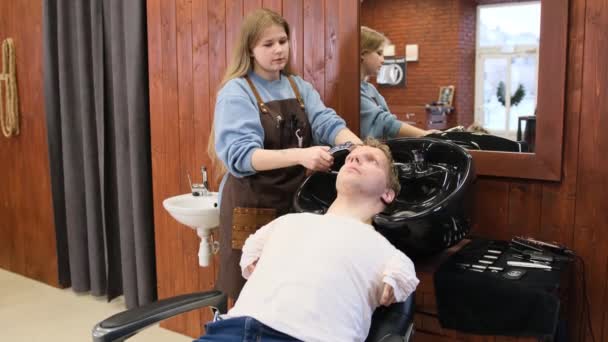 A hairdresser girl washes the hair of a man with limited opportunities in a beauty salon - Video