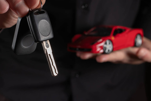 Male hand holding car key, car in the palm background, - Photo, Image