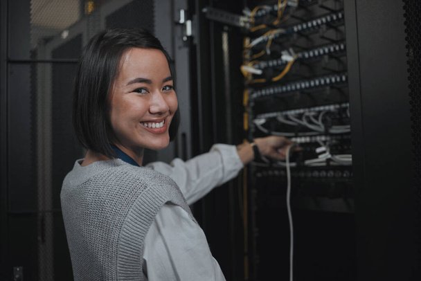 Asian woman, portrait smile and technician by server for cabling, networking or system maintenance at office. Happy female engineer smiling in cable service, power or data management or admin control. - Foto, Bild