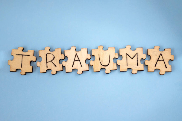 The word TRAUMA wooden written on the puzzles on a blue background. - Photo, Image