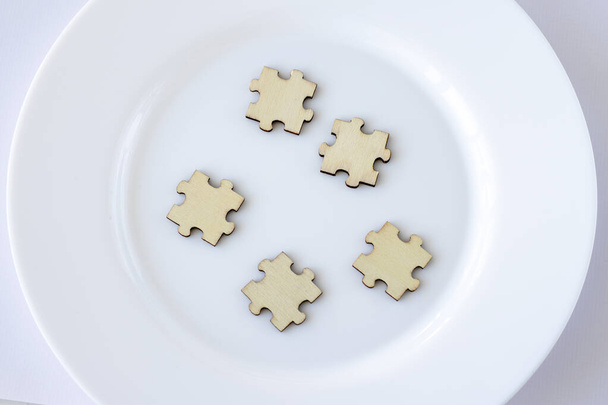 Eine Attrappe von fünf hölzernen Puzzles auf einem Teller. 5 Leerzeichen für die Beschriftung - Foto, Bild