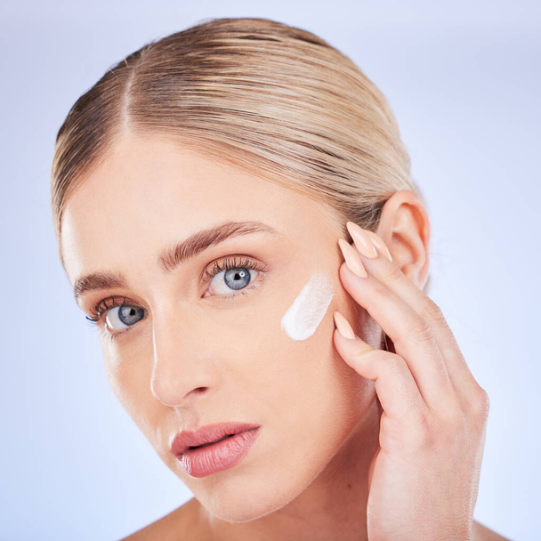 Skincare, face portrait and woman with cream in studio isolated on a blue background. Dermatology closeup, beauty cosmetics and young female model apply hydration lotion, creme or moisturizer product. - Foto, immagini
