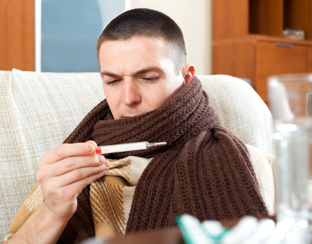 Sick  man looking at thermometer - 写真・画像